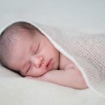 Portrait d'un nouveau né qui dort les bras croisés