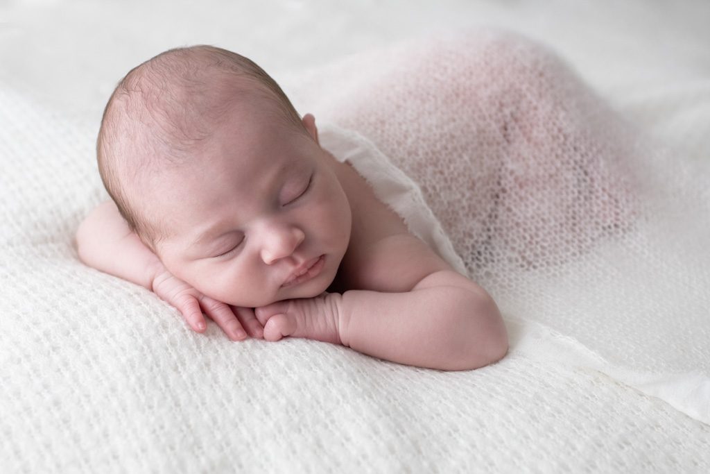 Portrait d'un nouveau né qui dort les bras croisés