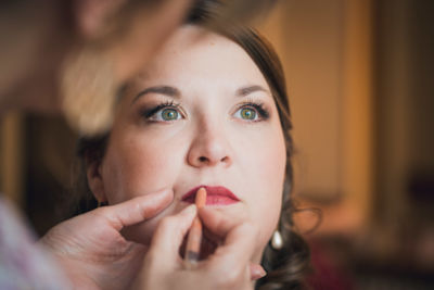 Portrait serré de la mariée qui se fait maquiller