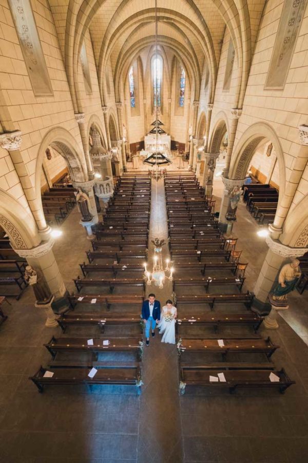 Vu du dessus des mariés qui avancent dans l'allée de l'église