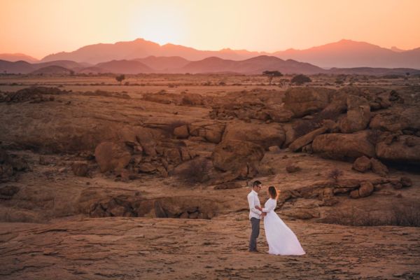 Couple d'amoureux au lever du soleil avec des montagnes et rochers rouges en arrière plan