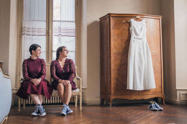Témoins de la mariée assises à côté de la robe de mariée suspendue à une armoire