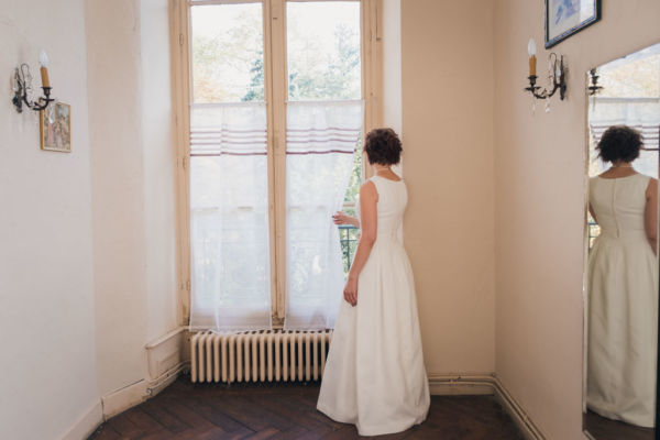 Mariée en robe qui regarde par la fenêtre