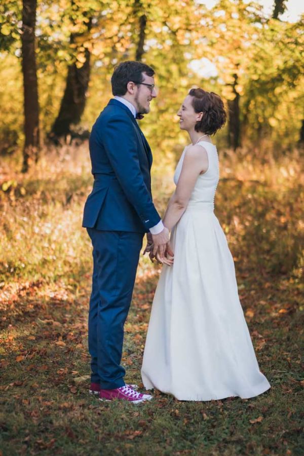 Couple de mariés face à face devant des arbres en automne