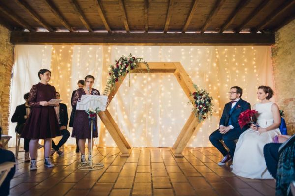 couple de mariés avec leurs témoins autour d'une arche en bois fleurie lors d'une cérémonie laïque