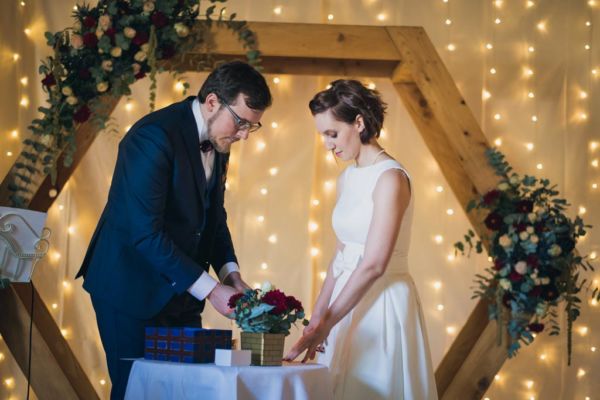 couple de mariés qui scellent leurs vœux sur une lettre cachée derrière des fleurs