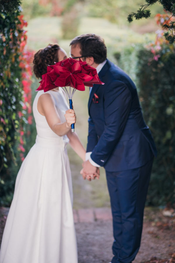 Couple de mariés qui s'embrassent cachés derrière le bouquet de la mariée