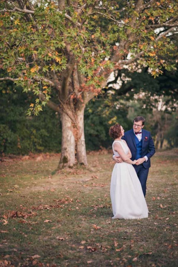 Couple de mariés enlacés devant un arbre