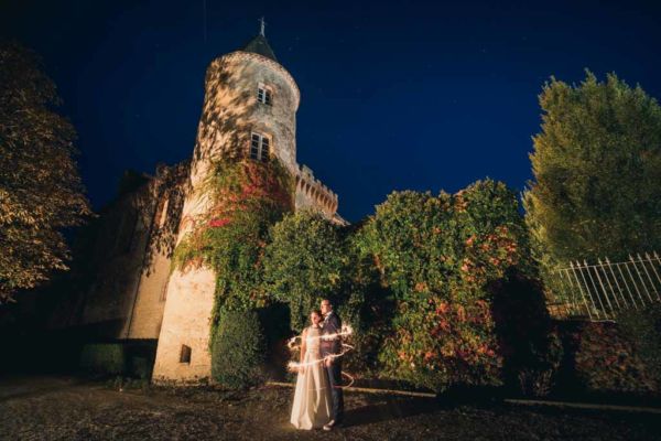 couple de mariés de nuit devant un château avec du lightpainting entourant le couple