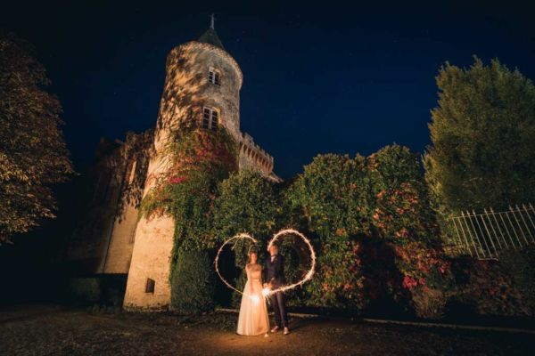 couple de mariés de nuit devant un château avec du lightpainting en forme de cœur