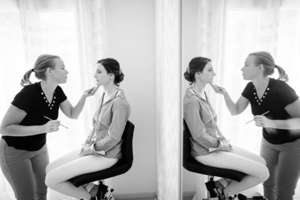 La mariée se fait maquiller, on voit le reflet des deux personnes dans un miroir