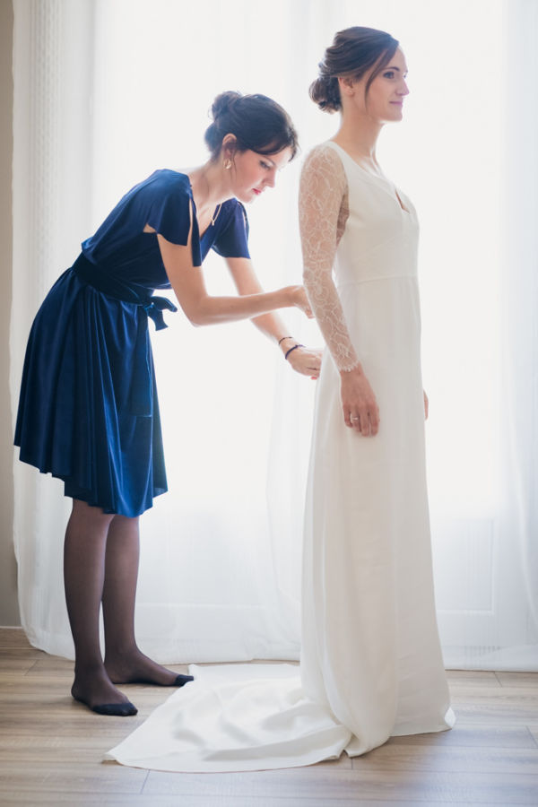 Une témoin ferme la robe de la mariée
