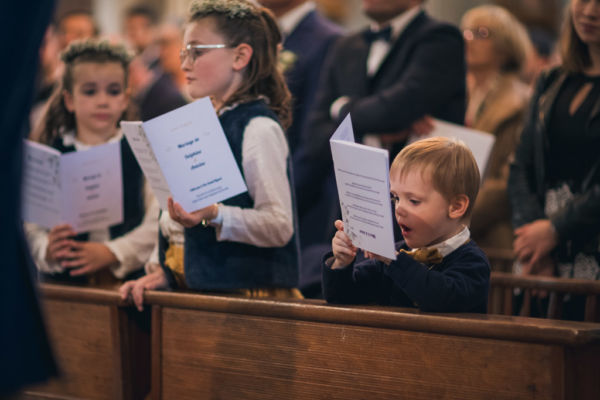 Dans l'église, un jeune garçon tient le livret de messe à l'envert