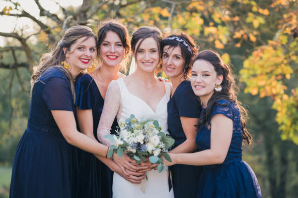 Mariée au milieu de ses demoiselles d'honneur, deux de chaque côté, elles tiennent toutes le bouquet de la mariée devant au centre