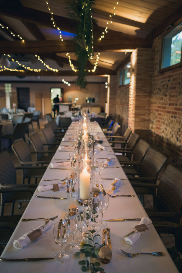 Table décorée du repas d'un mariage, avec des guirlandes lumineuses au plafond