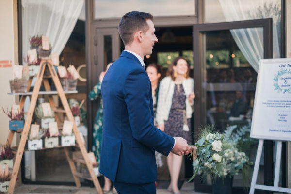 Le marié tient dans ses mains le bouquet de la mariée et s'apprête à le lancer vers les hommes célibataires derrière lui