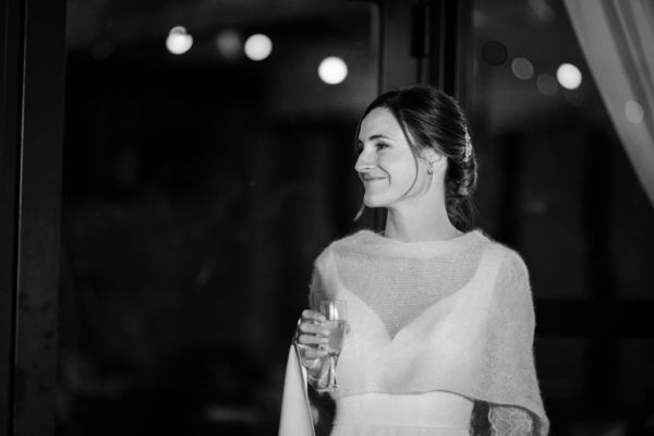 Mariée souriante un verre à la main lors du vin d'honneur